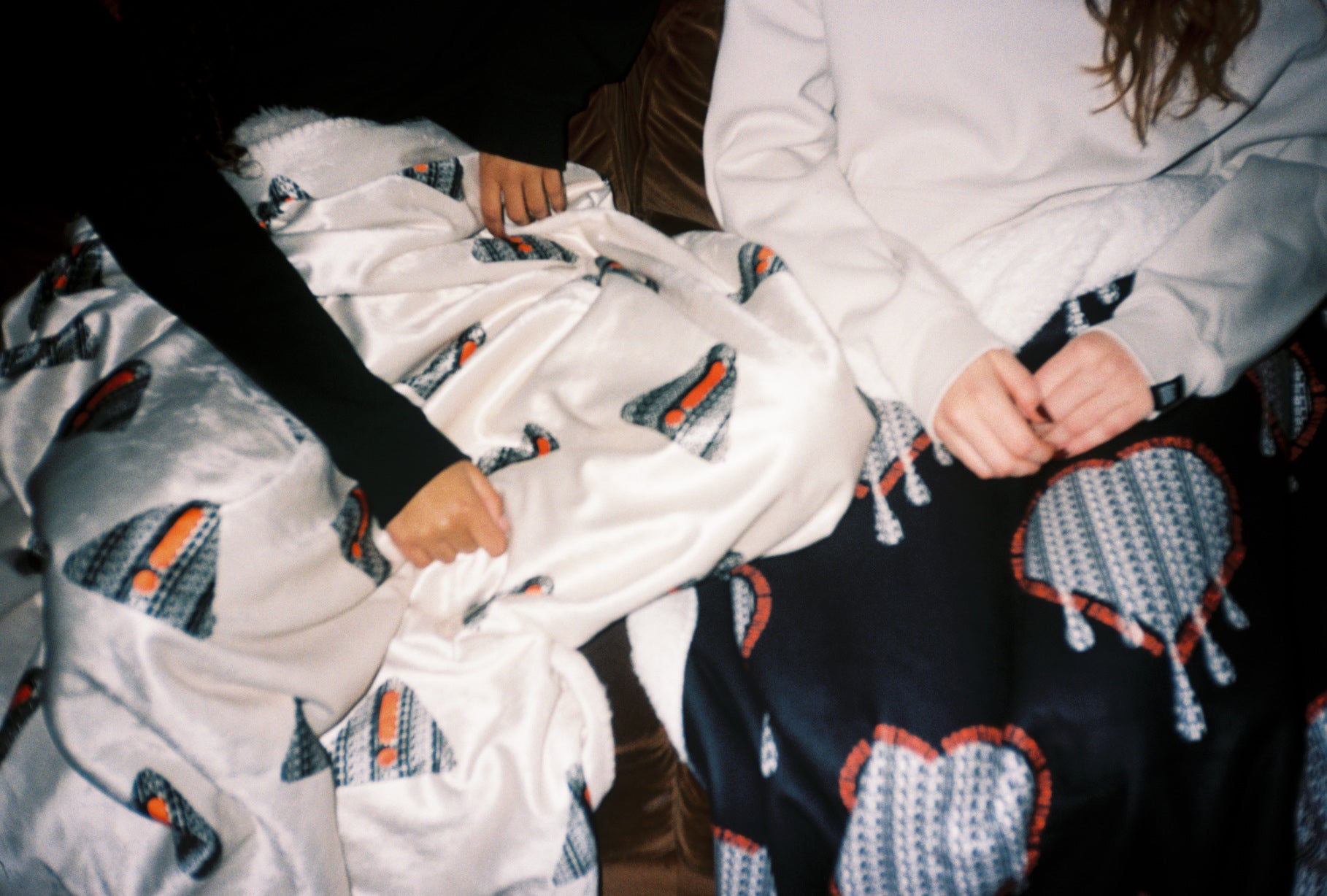 Two people sitting on a bed with a patterned blanket